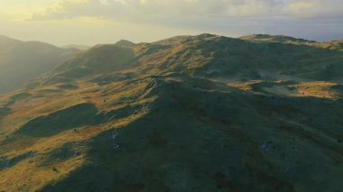 Hava 4K görüntüleri, sıcak altın saat ışığı altında alp sırtlarını ve çayırları gösteriyor..