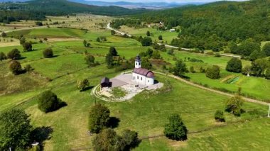 Svih Svetih kilisesinin ağaçlar, çayırlar ve dağınık evlerle çevrili insansız hava aracı görüntüleri..