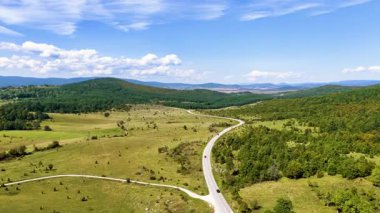 Bosna 'daki Glasinac platosunda arabaların geçtiği kırsal yolun insansız hava aracı videosu..