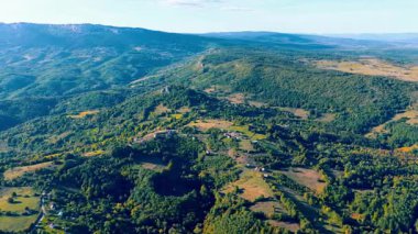 Romanija 'daki küçük köylerin üzerinde uçan hava aracı daireleri, geleneksel kırsal evleri, yeşil otlakları ve etrafındaki dağ sırtlarını gösteriyor..