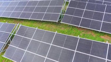 İnsansız hava aracı güneş çiftliğinin üzerinde uçuyor, fotovoltaik sıraları otlaklar arasında yakalıyor, çevre dostu yenilenebilir enerjiyi sembolize ediyor.