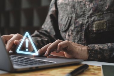 Uyarı sistemi sorunu dikkatli olmalı, veri sızıntılarını ve bakım sistemi konseptini önlemeli, kamuflaj üniformalı asker uyarı simgesi ile dizüstü bilgisayarda çalışmalıdır.