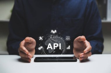 API veya Uygulama Programı Arayüzü, akıllı telefon ve çevrimiçi uygulama kavramına sahip programcı ve akıllı telefonun elleri.