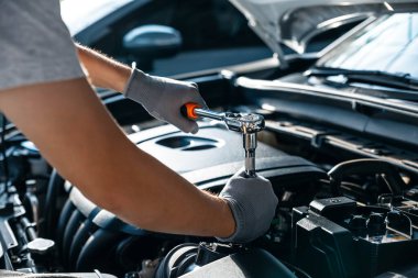 Tamirci, garaj atölyesinde araba motoru, araba servisi ve bakım konsepti üzerinde çalışırken ingiliz anahtarı kullanıyor..