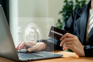 Çevrimiçi bankacılık kavramı, cep telefonu ve kredi kartı kullanan iş kadınları ve dizüstü bilgisayar ekranında göstergeleri olan dijital banka simgesi.