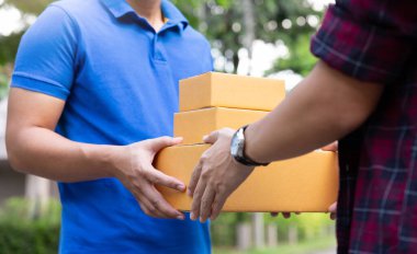 Çevrimiçi alışveriş ya da lojistik konseptinden paket alan genç adamın eli.