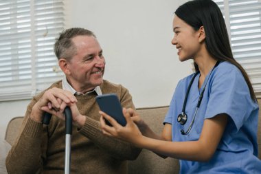 Mutlu hemşire yaşlı bir adama klinikte akıllı telefonla yardım eder, yaşlılara sağlık yardımı yapar..