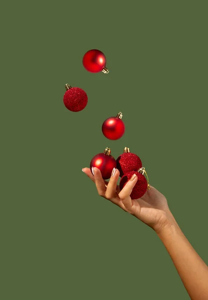 Wanita Cantik Tangan Juggling Perhiasan Natal Pada Latar Belakang Hijau — Stok Foto
