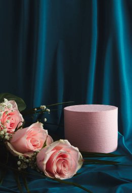 Suitable for Product Display and Business Concept. Product podium and pastel pink flowers. Blue silk curtain background. Modern aesthetic.
