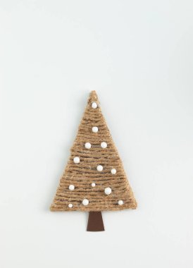 Handmade yarn cone xmas tree in natural color on white background with copy space. Minimal winter nature holiday scene. Concept of winter creativity and Christmas crafts, eco friendly.
