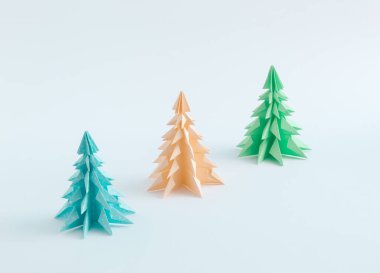 Three origami Christmas trees made with paper isolated on white background. Happy holidays. New Year minimal concept.
