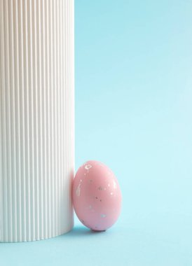 Gökyüzünde pembe Paskalya yumurtası mavi arka plan ve beyaz sütun. Minimum festival konsepti. Soyut Paskalya kartı. Boşluğu kopyala.