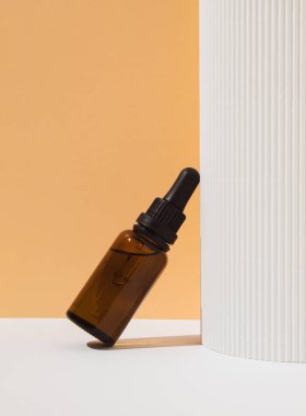 Cosmetic serum Vitamin C in brown glass bottle with pipette dropper on white and pastel orange background. Beauty cosmetics concept. Natural skin care Cosmetics. Makeup product.