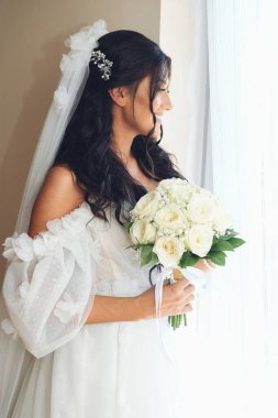 Damat için heyecanlı bir an, düğün günü, pencereden dışarı bakan tanınmayan bir gelin. Bir buket beyaz gül çiçekli genç bayan. Kutlama için gelin toplantısı kavramı.