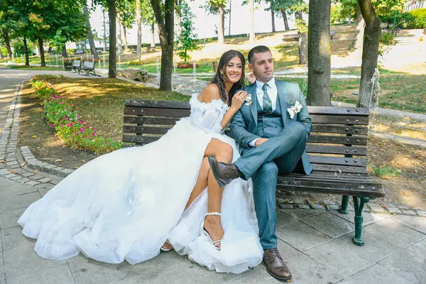 Çekici bir düğün çifti bankta oturur. Güzel gelin ve damat açık havada huzurlu bir anın tadını çıkarıyorlar..