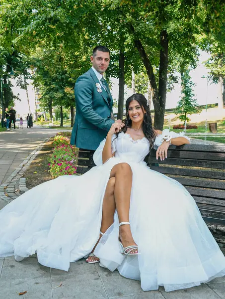 Çekici bir düğün çifti bankta oturur. Güzel gelin ve damat açık havada huzurlu bir anın tadını çıkarıyorlar..