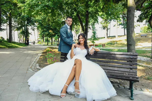 Çekici bir düğün çifti bankta oturur. Güzel gelin ve damat açık havada huzurlu bir anın tadını çıkarıyorlar..