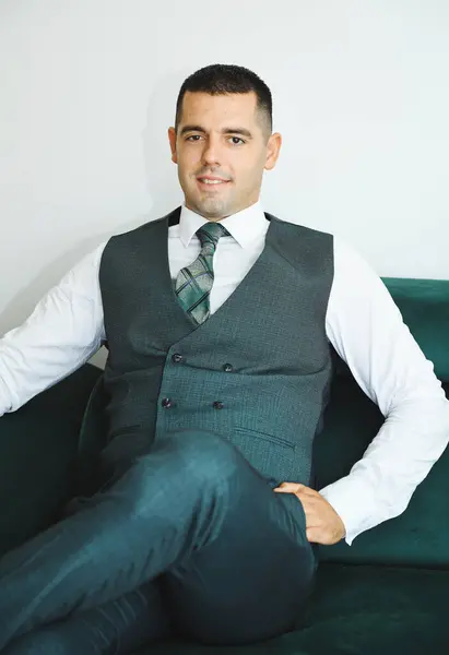 Koyu yeşil takım elbiseli bir damadın portresi. Zarafet ve güven saçıyor. Düğün kutlaması konsepti.