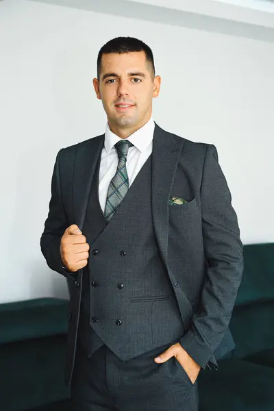 Koyu yeşil takım elbiseli bir damadın portresi. Zarafet ve güven saçıyor. Düğün kutlaması konsepti.