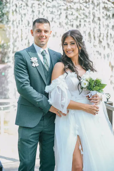 Gelin ve damat açık havada huzurlu bir anın tadını çıkarıyorlar. Düğün günlerinde şelalenin önünde kalan genç çift..