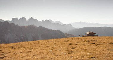 Sonbaharda harika bir manzarası olan Dolomitler 'deki bir dağın tepesinde tek kişilik bir kabin.