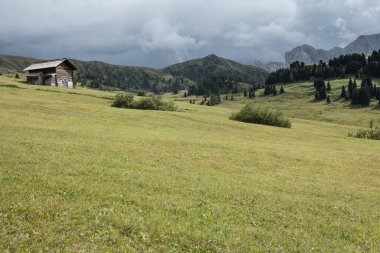Dolomitler 'de bir dağ otlağının üzerinde harika manzaralı küçük bir ev.