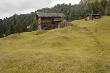 Dolomitler 'de bir dağ otlağının üzerinde harika manzaralı küçük bir ev.
