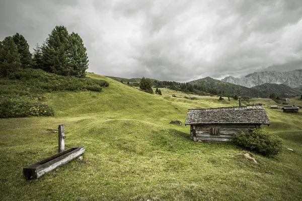 Dolomitler 'de bir dağ otlağının üzerinde harika manzaralı küçük bir ev.