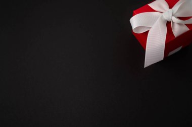 Siyah arka planda beyaz kurdeleli kırmızı hediye kutusu. Noel konsepti. Boşluğu kopyala.
