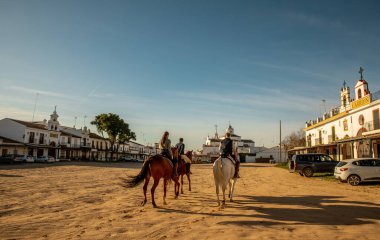 El Rocio kasabasındaki kumlu bir sokaktan geçenler