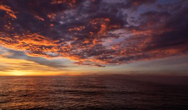 Denizin üzerinde gün doğumu ve dramatik kırmızı bulutlar, doğa arka planları okyanus ve Günbatımı Bulutları 