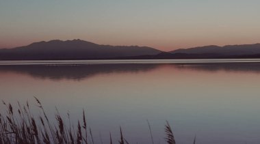 hazy sunset landscape of the etang de canet lagoon in France, Nature backgrounds water and mountains  clipart