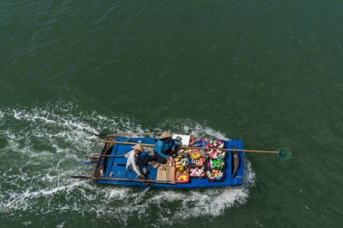 Tüccarlar Halong Körfezi 'ndeki turistlere mal teklif ediyorlar.