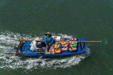 Tüccarlar Halong Körfezi 'ndeki turistlere mal teklif ediyorlar.