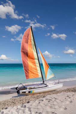 Varadero sahilinde renkli yelkenli katamaran - Küba. Turkuaz mavi Atlantik suyu ve beyaz bulutlu mavi gökyüzü..