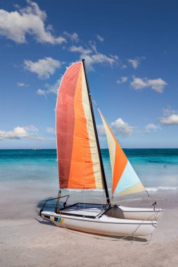 Varadero sahilinde renkli yelkenli katamaran - Küba. Turkuaz mavi Atlantik suyu ve beyaz bulutlu mavi gökyüzü..