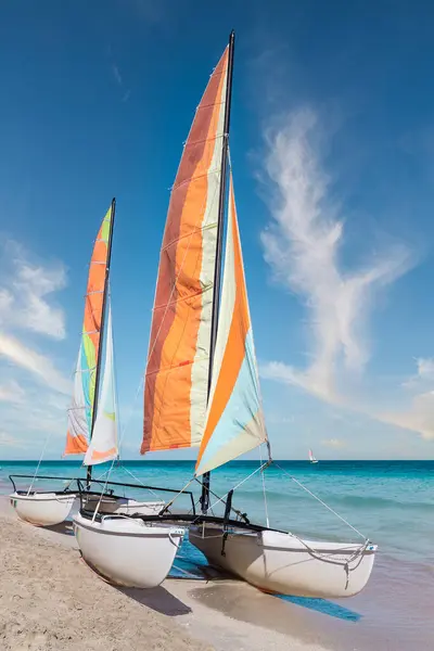 Varadero sahilinde renkli yelkenli katamaran - Küba. Turkuaz mavi Atlantik suyu ve beyaz bulutlu mavi gökyüzü..