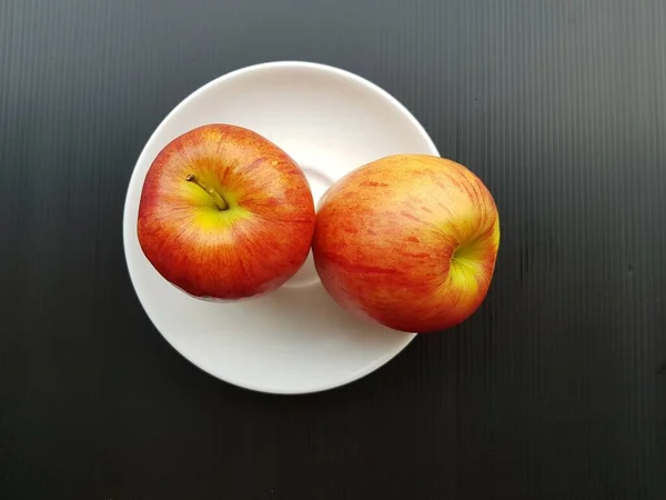 Δύο Ώριμα Κόκκινα Μήλα Ένα Πιάτο Μαύρο Φόντο — Φωτογραφία Αρχείου