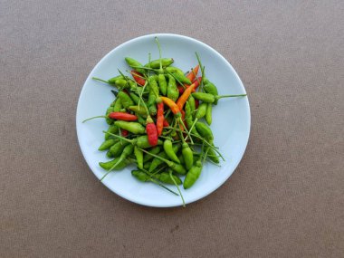 Kahverengi arka planda beyaz tabak üzerine kırmızı biber..