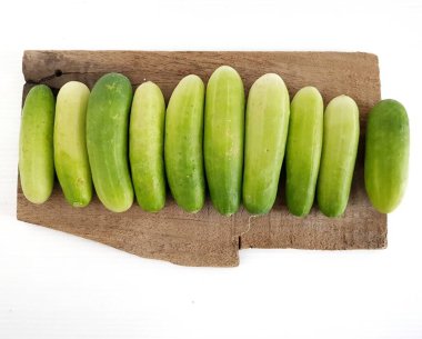 Üst manzara: Muz yaprağı ambalajında taze salatalık. Beyaz arkaplanda sebze.