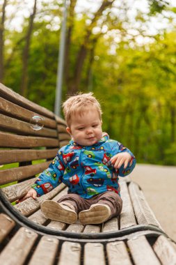 portrait of a little boy in the park on a bench catching soap bubbles close-up