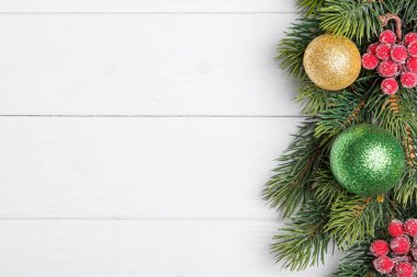 Beyaz ahşap arka planda koni ve oyuncakları olan bir Noel ağacının güzel dalları.