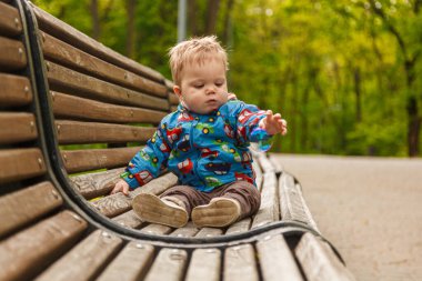 Parkta bir bankta sabun köpüğü yakalayan küçük bir çocuğun portresi.