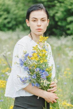 Yaz tarlalarının arasında kır çiçekleriyle güzel bir kız.