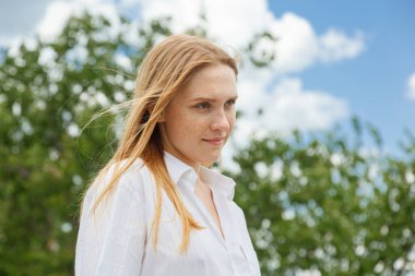 Beyaz gömlekli ve turuncu etekli güzel kız mavi gökyüzüne ve bulutlara karşı