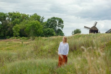 Beyaz gömlekli ve turuncu etekli güzel kız mavi gökyüzüne ve bulutlara karşı