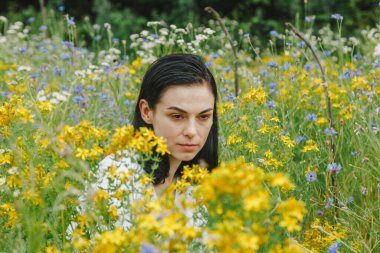 Yaz tarlalarının arasında kır çiçekleriyle güzel bir kız.