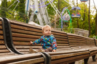 Parkta bir bankta sabun köpüğü yakalayan küçük bir çocuğun portresi.