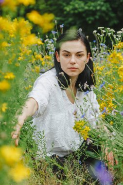 Yaz tarlalarının arasında kır çiçekleriyle güzel bir kız.