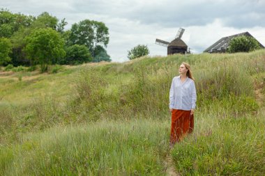Beyaz gömlekli ve turuncu etekli güzel kız mavi gökyüzüne ve bulutlara karşı